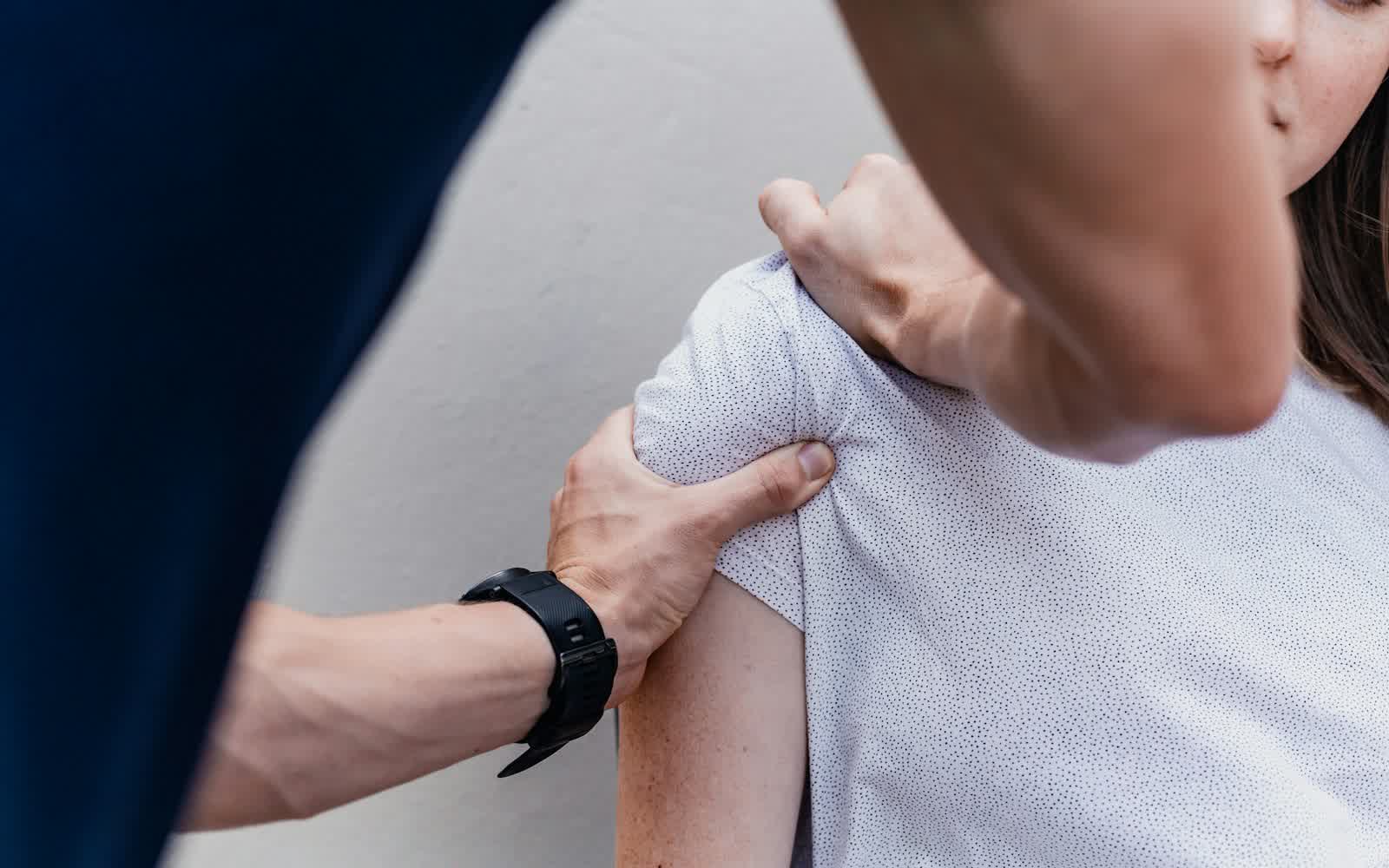 A physical therapist assessing a patient's shoulder in a clinic